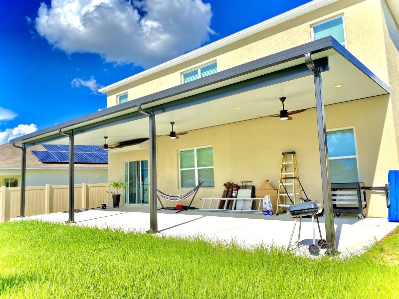 yellow home with patio cover and work equipment