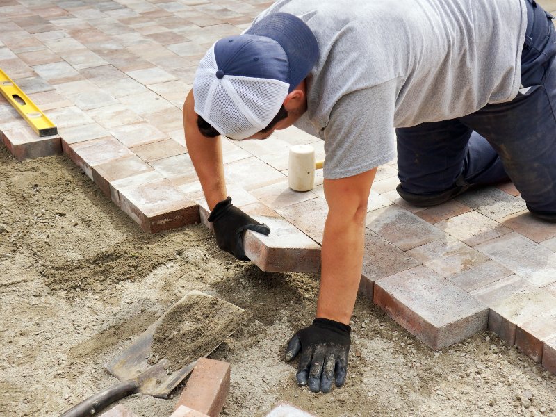 professional in gray shirt installing pavers