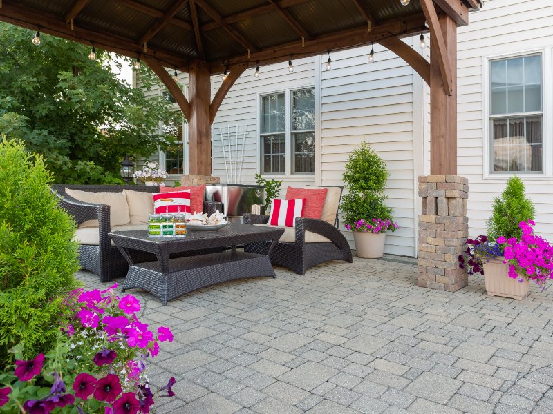 white home with pavers and black furniture and plants