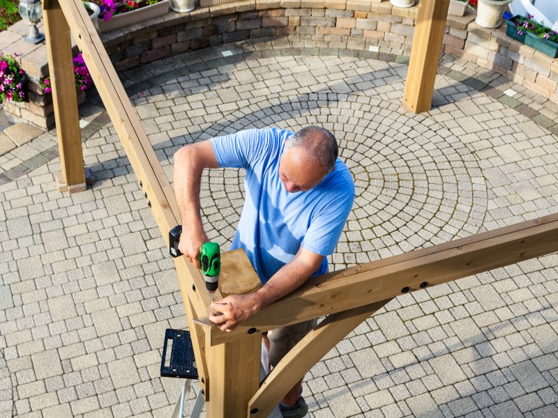 professional in blue shirt working on pergola installation